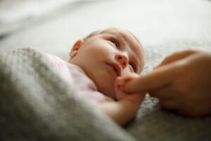 Baby hält Augenkontakt zur Mutter und umgreift ihren Finger ihrer Hand